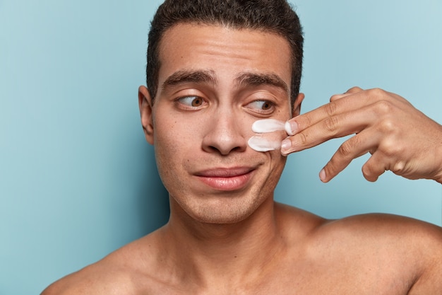 Portrait de jeune homme appliquant la crème