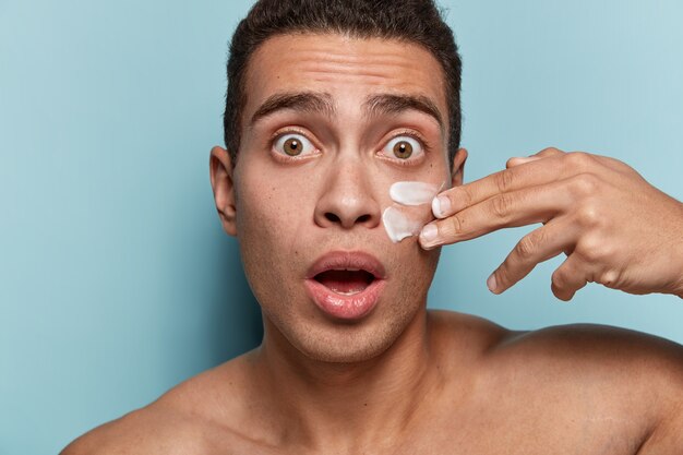 Portrait de jeune homme appliquant la crème