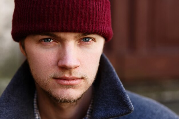 Portrait de jeune homme au chapeau rouge posant dehors