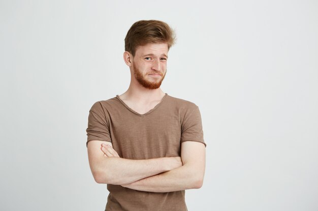 Portrait de jeune homme beau avec barbe avec mépris les bras croisés.