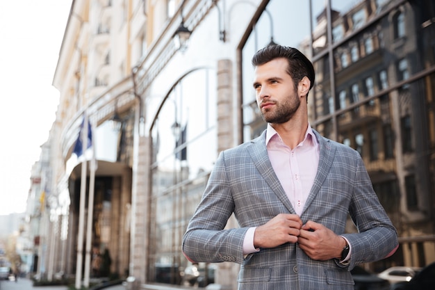 Portrait d'un jeune homme beau boutonner sa veste