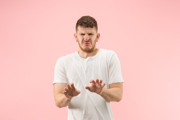 Portrait de jeune homme branché sur fond rose. Expression émotionnelle.