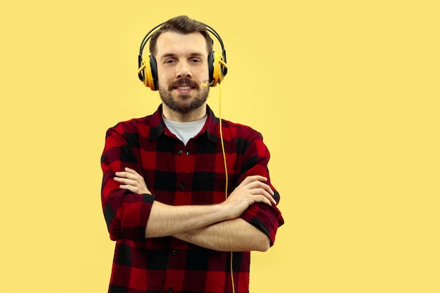 Portrait de jeune homme avec un casque sur mur jaune