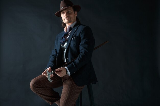 Portrait de jeune homme avec un chapeau sur fond gris studio.