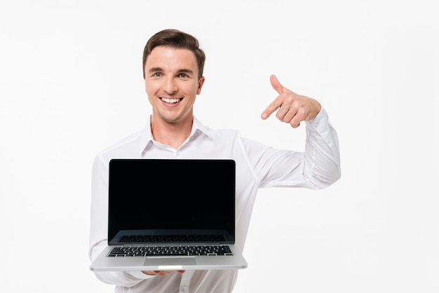 Portrait d'un jeune homme confiant en chemise blanche pointant