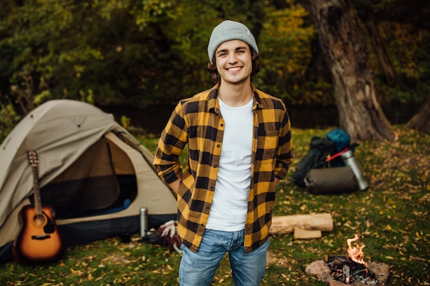 Portrait de jeune homme debout dans la forêt avec tente