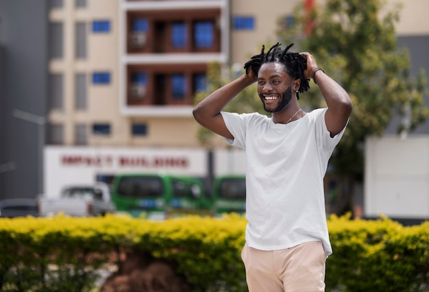 Portrait de jeune homme avec des dreadlocks afro et un t-shirt blanc à l'extérieur