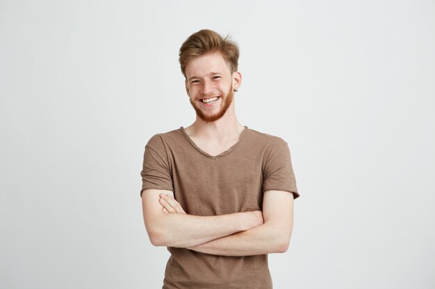 Portrait de jeune homme gai heureux avec barbe souriant avec les bras croisés.