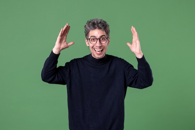 Portrait d'un jeune homme de génie habillé avec désinvolture en studio tourné heureux et heureux sur un mur vert