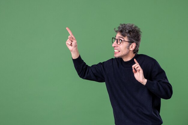 Portrait de jeune homme de génie habillé avec désinvolture en studio tourné sur mur vert