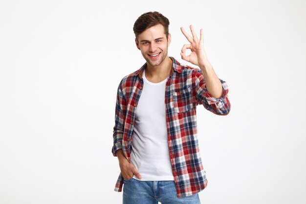Portrait d'un jeune homme heureux montrant le geste ok
