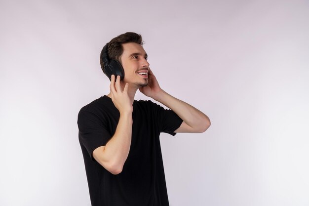Portrait d'un jeune homme heureux portant un casque et écouter de la musique sur fond blanc