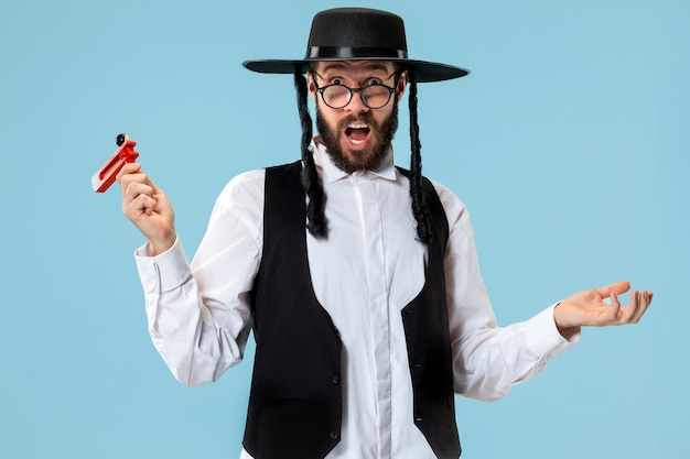 Portrait d'un jeune homme juif orthodoxe avec cliquet grager en bois pendant le festival Pourim.