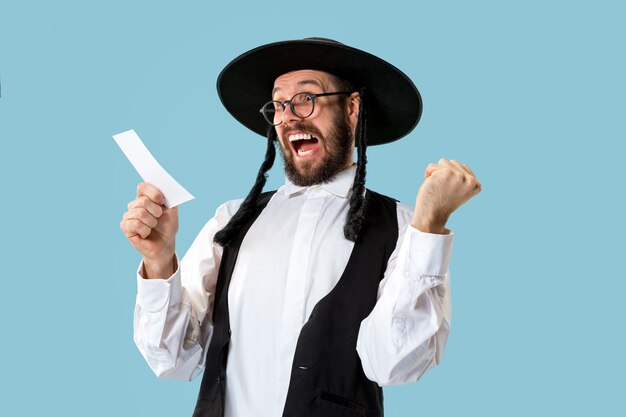 Portrait d'un jeune homme juif orthodoxe avec coupon de pari au studio.