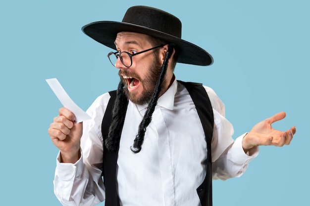 Portrait d'un jeune homme juif orthodoxe avec coupon de pari au studio.