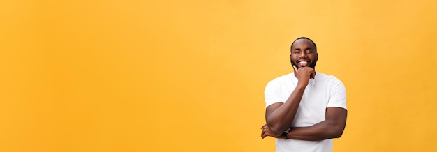 Photo gratuite portrait d'un jeune homme noir moderne souriant avec les bras croisés sur fond jaune isolé