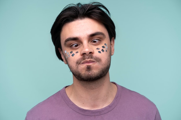 Photo gratuite portrait d'un jeune homme portant des confettis sur son visage et faisant une grimace idiote