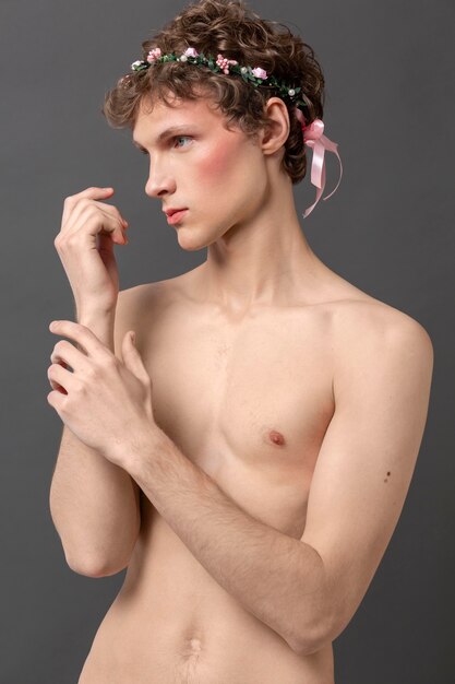 Portrait jeune homme portant maquillage et couronne de fleurs