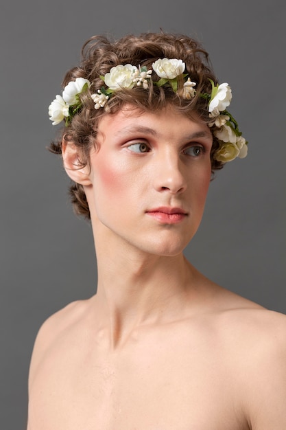 Portrait jeune homme portant maquillage et couronne de fleurs