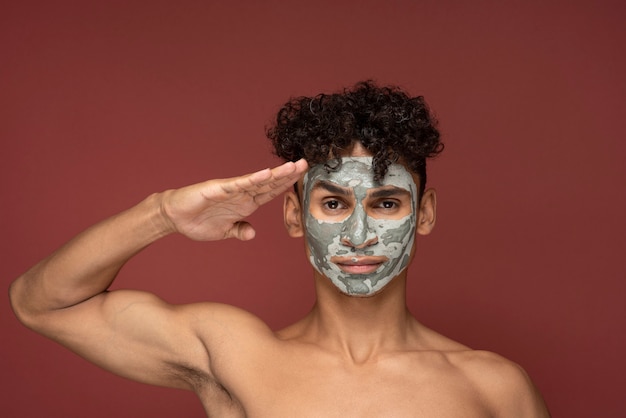 Portrait d'un jeune homme posant avec un masque de beauté dessus