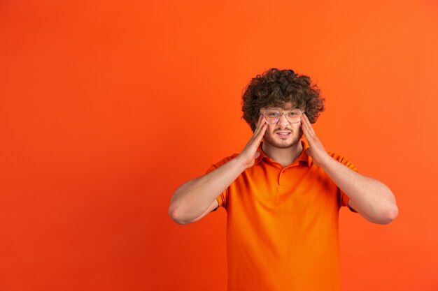 Portrait de jeune homme de race blanche avec des émotions vives sur studio orange