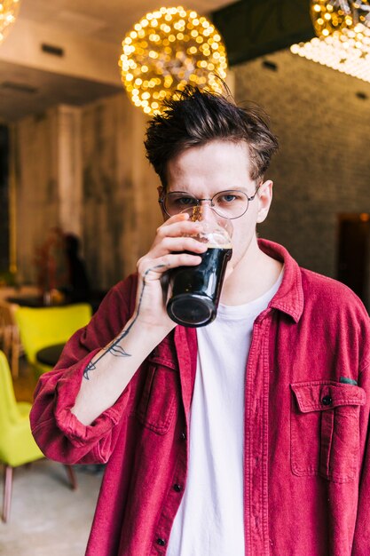 Portrait d&#39;un jeune homme regardant la caméra en buvant des verres à bière