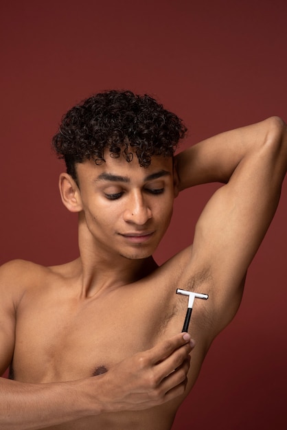 Photo gratuite portrait d'un jeune homme se rasant l'aisselle avec un rasoir