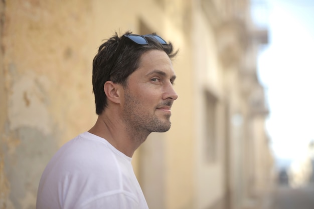 Photo gratuite portrait d'un jeune homme séduisant à lunettes de soleil posant près du mur par une journée ensoleillée