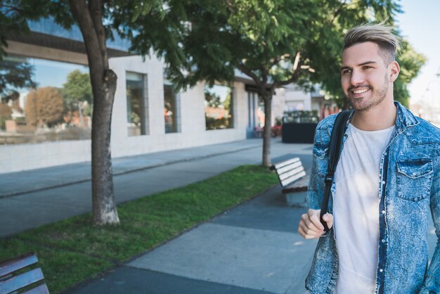 Portrait d'un jeune homme séduisant marchant dans la rue avec un sac à dos sur les épaules