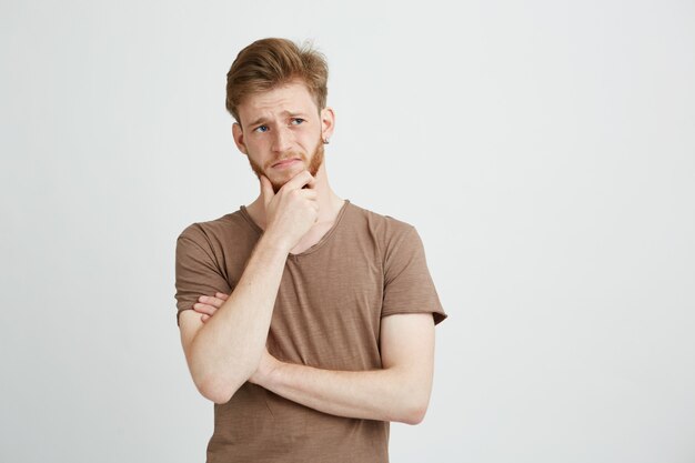 Portrait d'un jeune homme sérieux pensant à la recherche de côté.