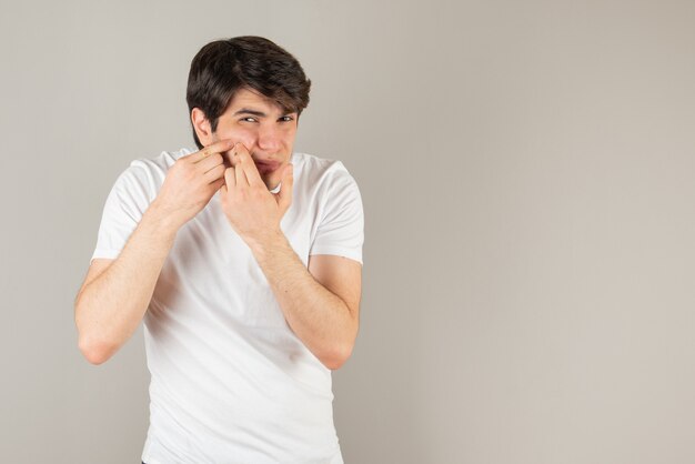 Portrait de jeune homme serrant son bouton contre le gris.