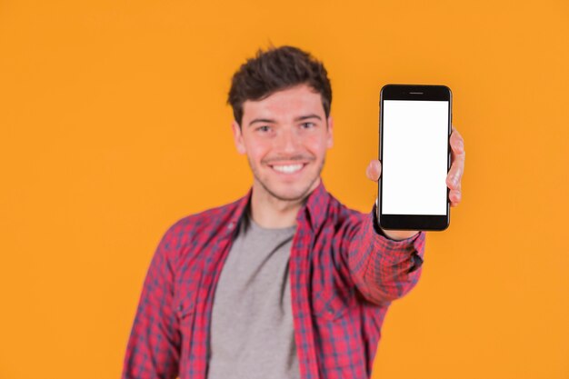 Portrait d&#39;un jeune homme souriant montrant un téléphone mobile à écran blanc vide