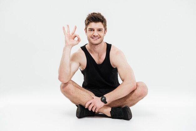 Portrait d'un jeune homme souriant de remise en forme en bonne santé assis