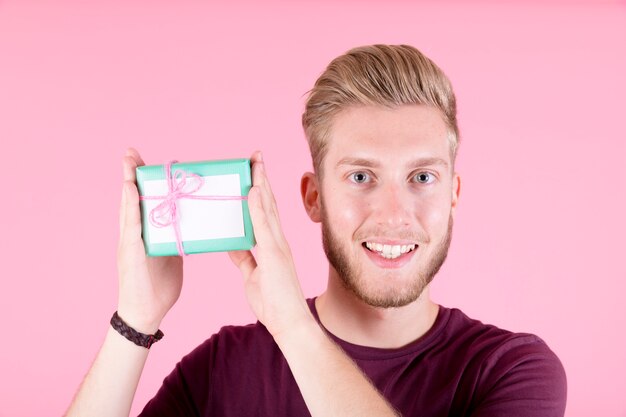 Portrait de jeune homme souriant tenant une petite boîte-cadeau