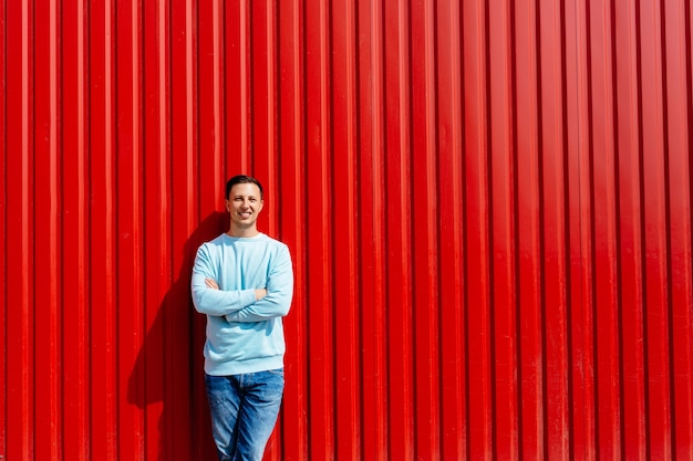 Portrait de jeune homme souriant en veste bleue sur le fond du mur rouge