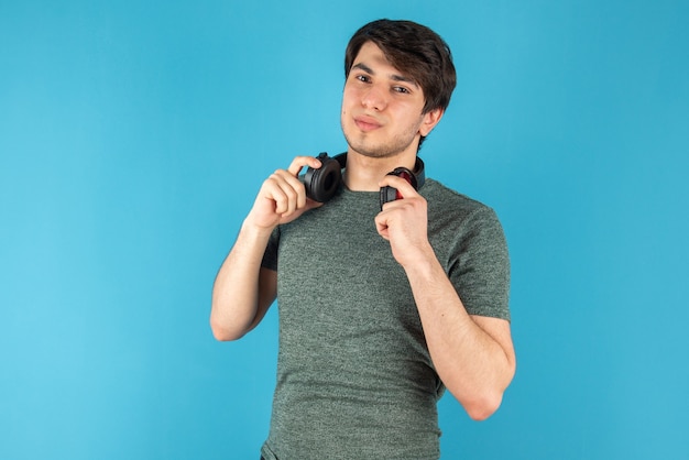 Portrait de jeune homme tenant un casque dans les mains contre le bleu.