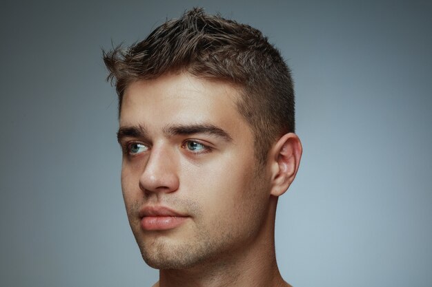 Portrait de jeune homme torse nu isolé sur fond gris studio. Modèle masculin en bonne santé caucasien regardant sur le côté et posant. Concept de la santé et de la beauté des hommes, des soins personnels, des soins du corps et de la peau.