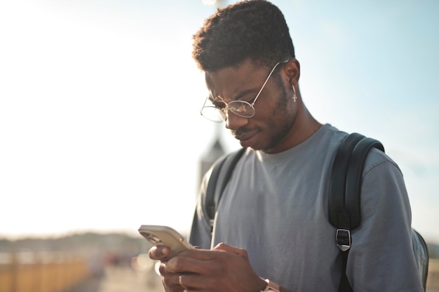 Photo gratuite portrait de jeune homme tout en utilisant un smartphone