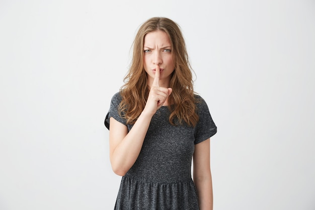 Portrait de jeune jolie fille fronçant les sourcils montrant directement garder le silence.