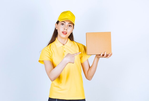 Portrait de jeune livreuse tenant une seule boîte sur blanc.