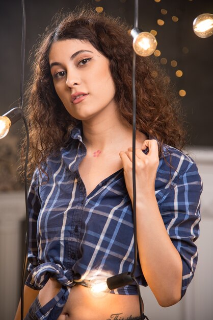 Portrait d'un jeune mannequin en chemise à carreaux posant près de lampes