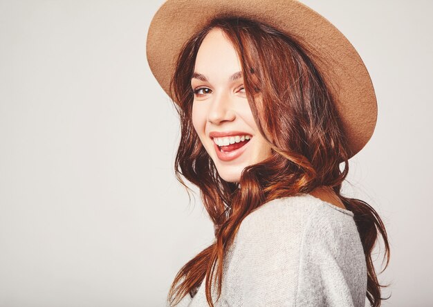 Portrait de jeune mannequin élégant en vêtements d'été gris décontracté en chapeau brun avec maquillage naturel