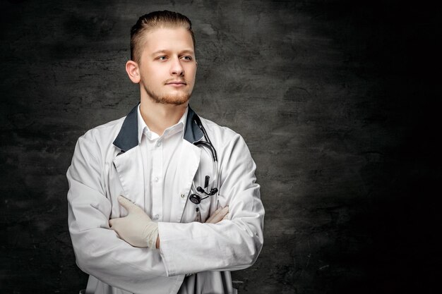 Portrait d'un jeune médecin confiant sur fond gris.