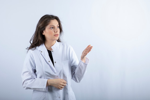 Portrait de jeune médecin en regardant quelque chose sur le mur blanc.