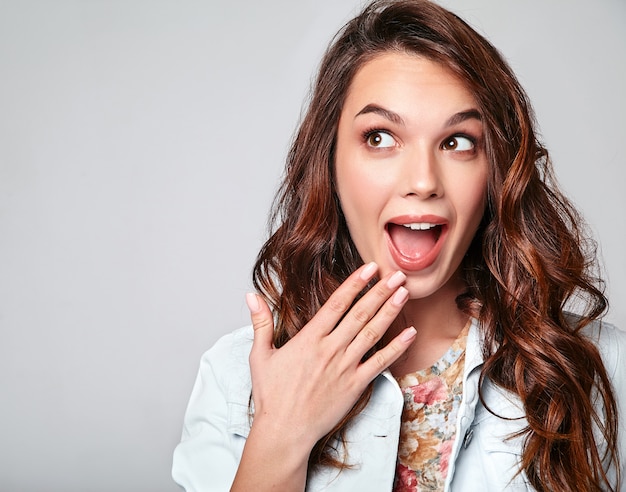 Portrait de jeune modèle riant élégant en vêtements d'été décontractés colorés avec du maquillage naturel sur gris