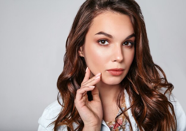 Portrait de jeune modèle riant élégant en vêtements d'été décontractés colorés avec du maquillage naturel sur gris