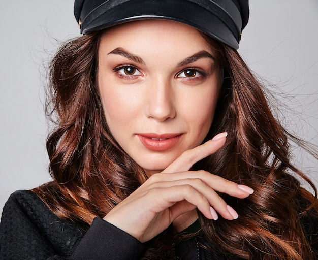 Portrait de jeune modèle riant élégant en vêtements d'été décontractés noirs en casquette avec maquillage naturel sur gris