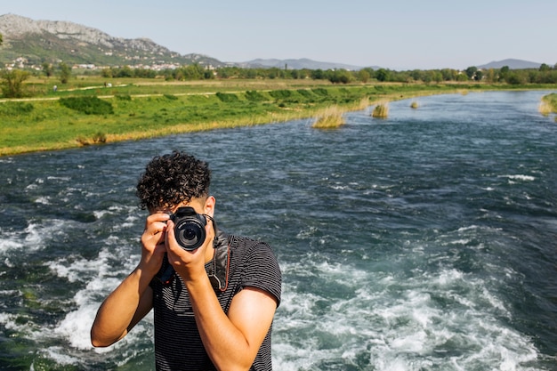 Photo gratuite portrait de jeune photographe prenant une photo devant la caméra