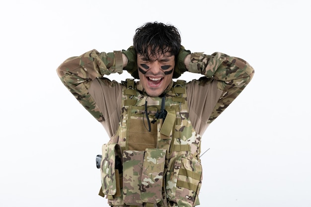 Portrait de jeune soldat en camouflage célébrant la victoire mur blanc