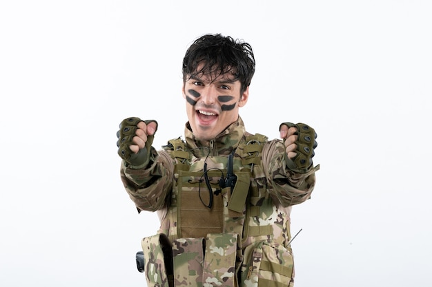 Portrait de jeune soldat en camouflage sur mur blanc